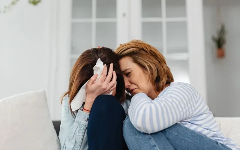 Two women share an emotional moment, conveying comfort and empathy indoors.
