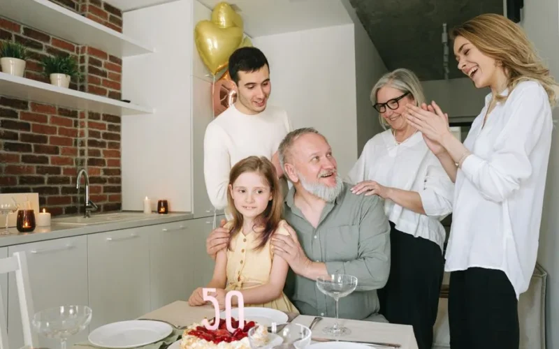 A joyful family celebration indoors with a birthday cake and balloons marking the 50th milestone.