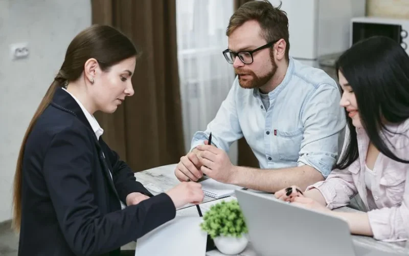 A couple discusses financial documents with their advisor, highlighting investment strategies.