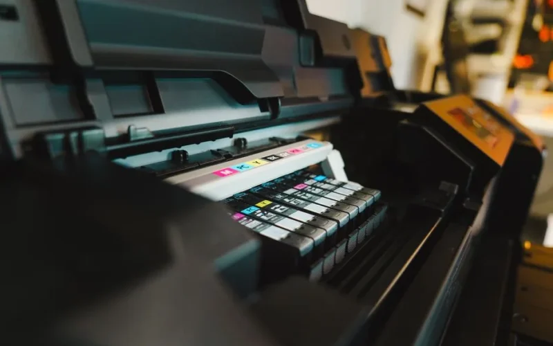 Detailed view of ink cartridges inside a digital inkjet printer in an office setting.