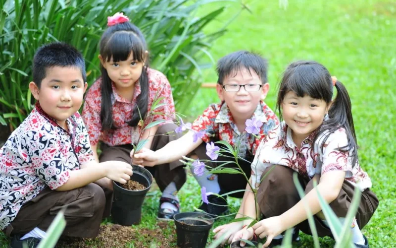 Group of happy children planting flowers together in a garden.