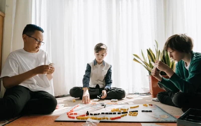 Three children deeply focused while playing a board game together indoors.