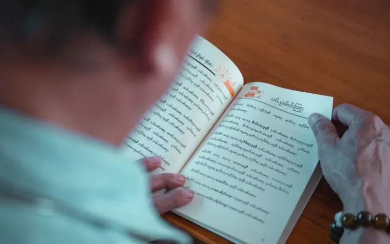 An adult reading a book with religious texts in Bangkok, Thailand.