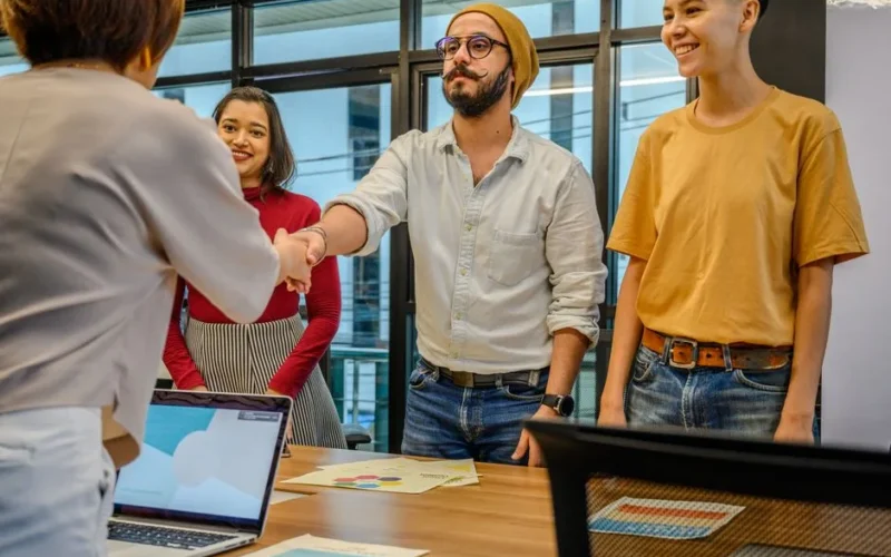 Colleagues shaking hands during a business meeting in a modern office setting.