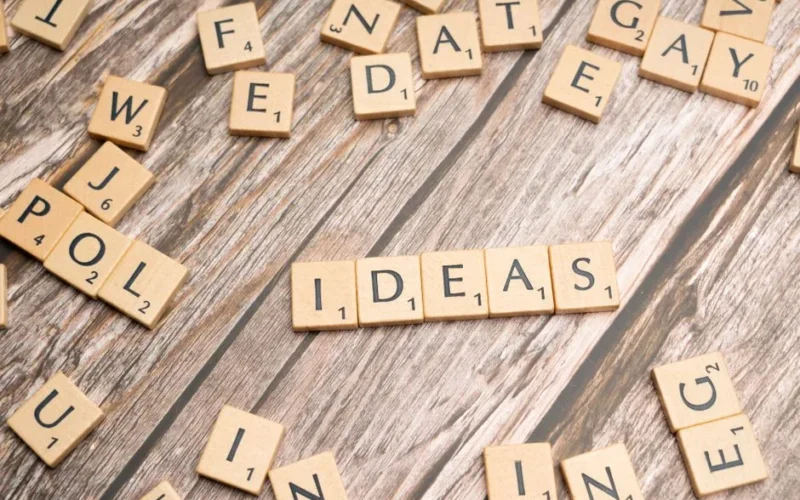 Scrabble word tiles forming 'IDEAS' on a wooden texture background, symbolizing creativity.