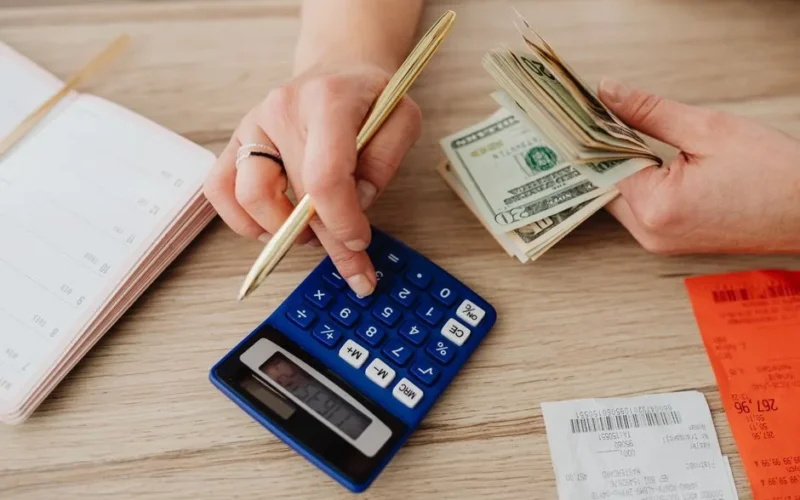 Hands handling cash and calculator for budget planning. Modern financial scene.