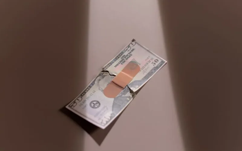 A $50 bill with a bandage symbolizes financial recovery and repair.