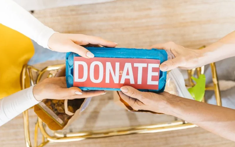 Hands exchanging a donation box filled with items, symbolizing giving and community support.