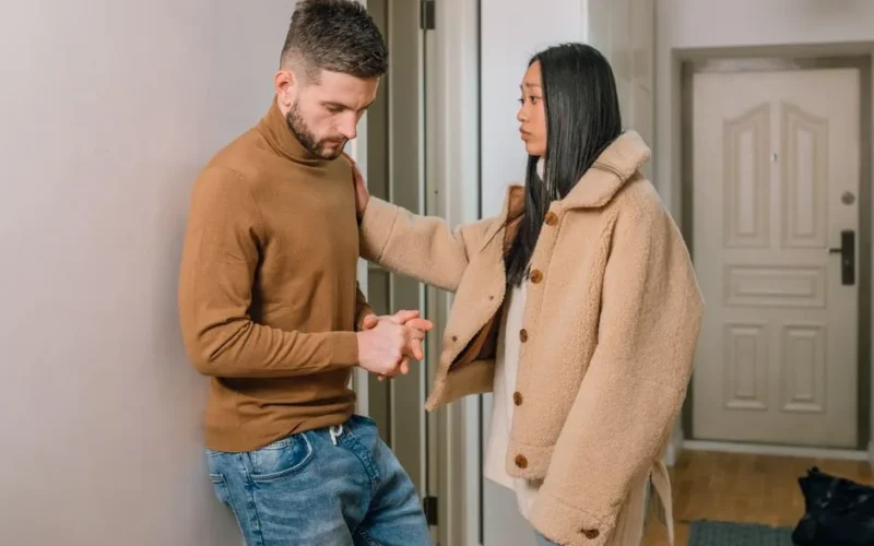 An interracial couple engaged in a serious conversation inside a home, showcasing emotion and connection.