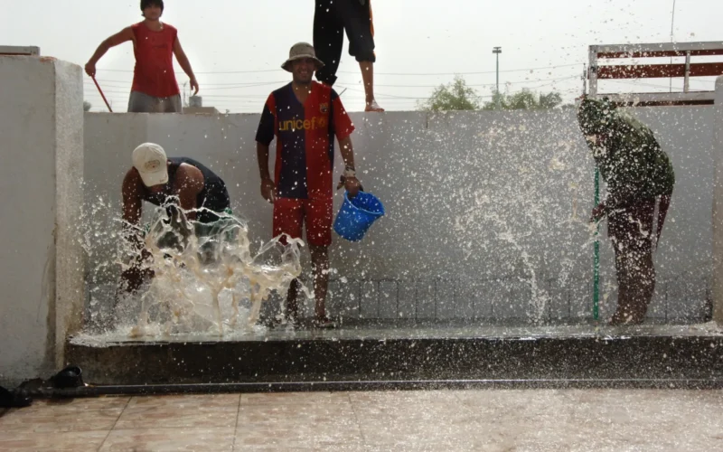 Pool employees push water from out of a foot bath as they clean the area in preparation for the grand opening of the al Jadida public swimming pool in Baghdad al Jadida, Eastern Baghdad, June 7, 2008.