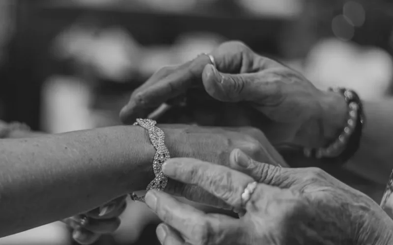 A detailed monochrome shot showing a bracelet being gently fastened on a wrist.