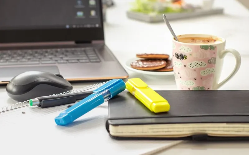 A bright and inviting workspace featuring a laptop, stationery, and a mug of coffee, perfect for productivity.