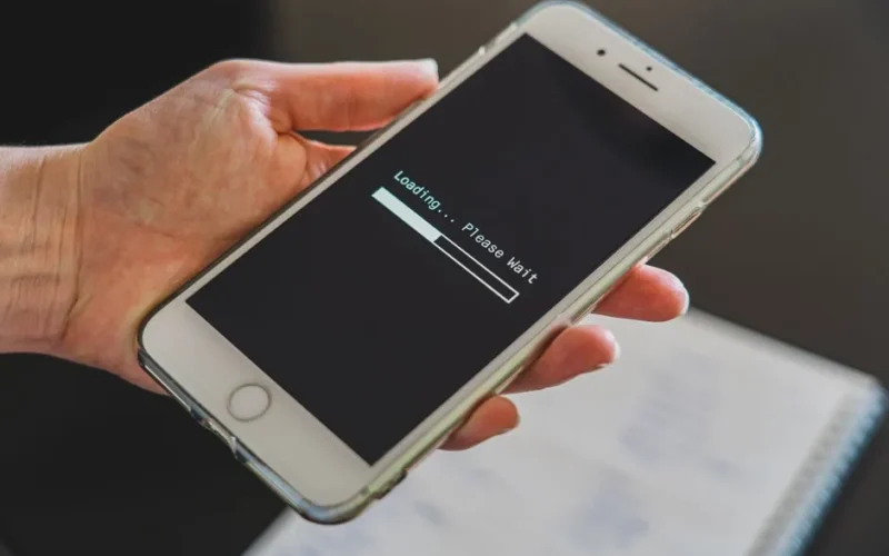 Close-up of a hand holding a smartphone with a loading screen displayed, showcasing technology usage.