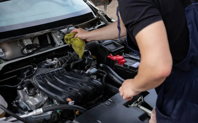 Close-up of mechanic repairing a car engine, focusing on maintenance and cleaning.