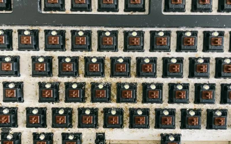 From above of keyboard panel without keycaps full of dust and dirt before cleaning