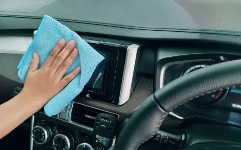 Crop anonymous person polishing panel in right hand drive car by using blue fiber cloth