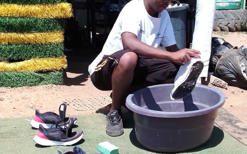 A man is cleaning, washing shoes on the street.