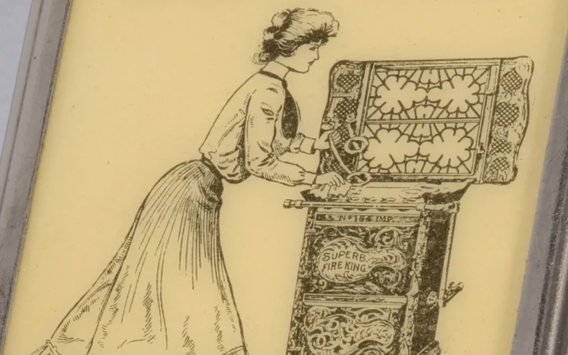 Rectangular, curved top and bottom, featuring black printed decoration of female in blouse, tie, long skirt, and upswept hair cleaning beneath range top, inscribed above "The Great White Enameled Top. Fire King Gas Ranges. Top Hinges Back. Burners Lift Out. Easily Kept Clean. Low in Price." Inscribed below "Manufactured By A. Weiskittel & Son, Baltimore, MD., U.S.A." Reverse features hot plate, inscribed above "A Match Is All The Kindling Required Where Fire King Gas Stoves And Ranges Are Used." Inscribed below "New Fire King Hot Plate With Hinged Top Gratings And Removable Drilled Burners." Inscribed in fine print below "The Whitehead & Hoag Co., Newark, N.J." Lid hinged on side. Striker on bottom.