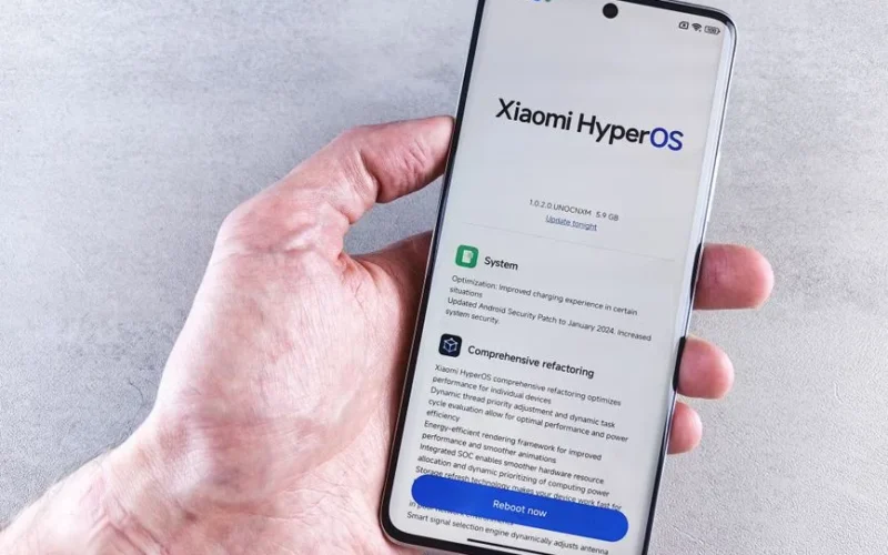 Close-up of a hand holding a Xiaomi smartphone with HyperOS interface, showcasing comprehensive refactoring and system update details.