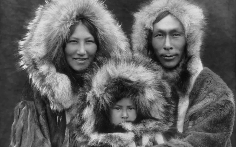 A family portrait of an Inupiat Eskimo mother, father, and son. Photographed in Noatak, Alaska, circa 1929. From The North American Indian, by Edward S. Curtis. The scan was made from a black and white film copy negative.