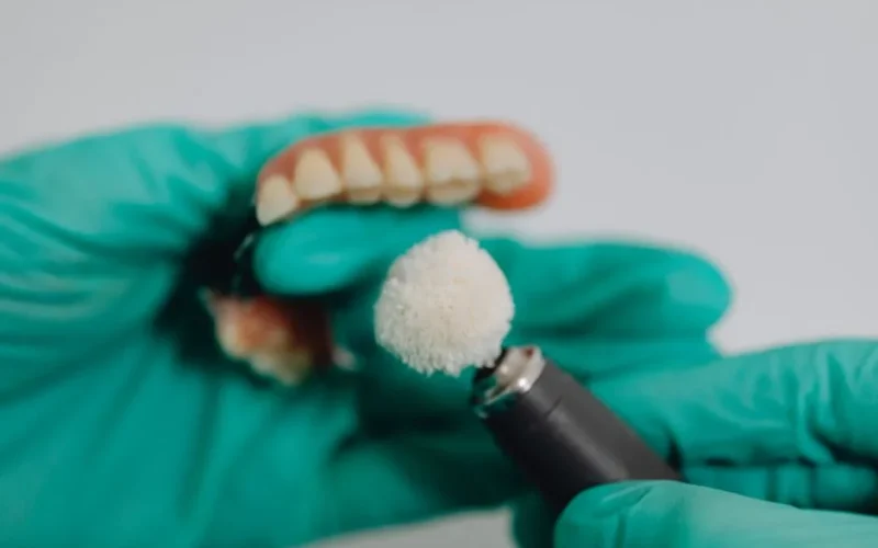 Detailed image of dentures being polished by a dental professional wearing gloves. Ideal for dental care topics.