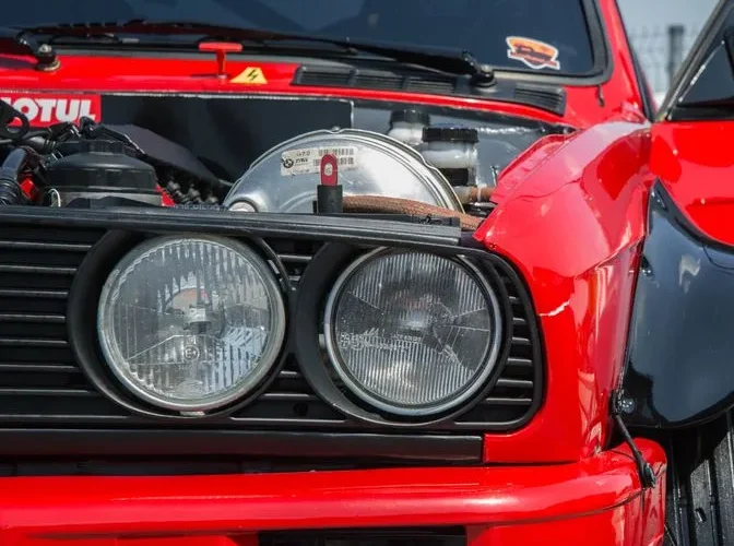 Detailed close-up of vintage red sports car headlights showcasing classic automotive design.
