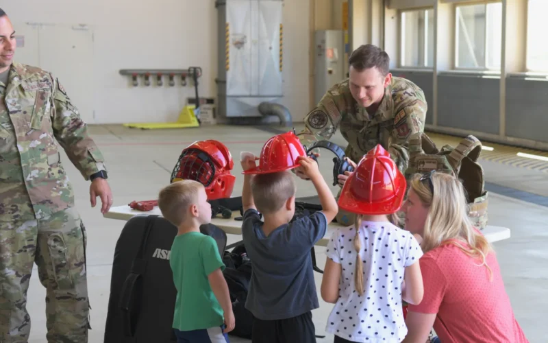 A U.S. Air Force Airman from the 86th Maintenance Group helps a child with a set of headphones at Ramstein Air Base, Germany, May 20, 2022. Different booths were set up throughout the event to help Open House attendees learn more about the capabilities of the maintenance group. (U.S. Air Force graphic by Airman 1st Class Lauren Jacoby)