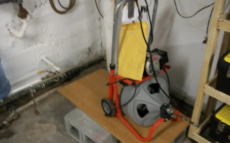 Cleaning a clogged drain is tough work; a professional caliber drain cleaning machine slowly spins a snaking cable. With a foot pedal, both arms are free to feel for tension on the cable as it spins in the drain. Different cable heads are used for different purposes.