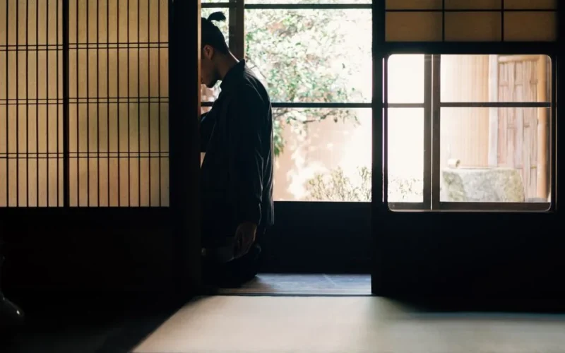 A person meditates in a tranquil Japanese room with soft light filtering through shoji screens.
