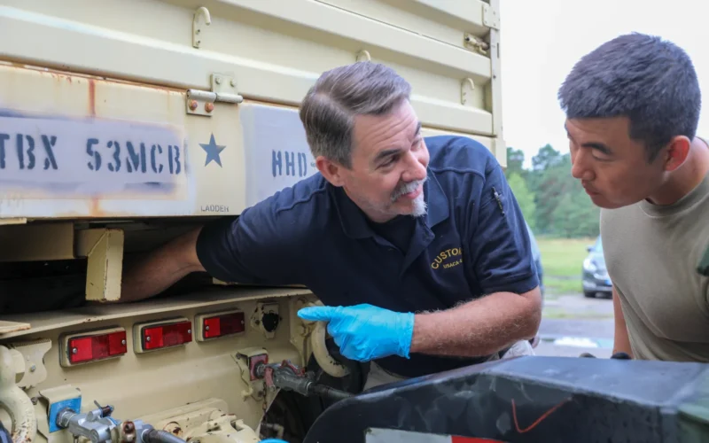 Mr. Steven J. Houll, the chief inspector with U.S. Army Customs Agency-Europe, instructs Sgt. Zheming Li, the logistics noncommissioned officer in charge with the 53rd Movement Control Battalion, 7th Transportation Brigade (Expeditionary), where to pressure wash a Light Medium Tactical Vehicle (LMTV) in Żagań, Poland, July 9, 2021. The 53rd conducted redeployment operations near the end of a nine-month rotation to Poland in support of Atlantic Resolve. Operation Atlantic Resolve demonstrates the continued commitment of the United States to the collective security of NATO. U.S. Army Customs Agency-Europe's mission is to provide efficient and effective infrastructure and services ensuring U.S. Army Europe’s readiness while in host nations. (U.S. Army photo by Staff Sgt. Jennifer Reynolds/released)