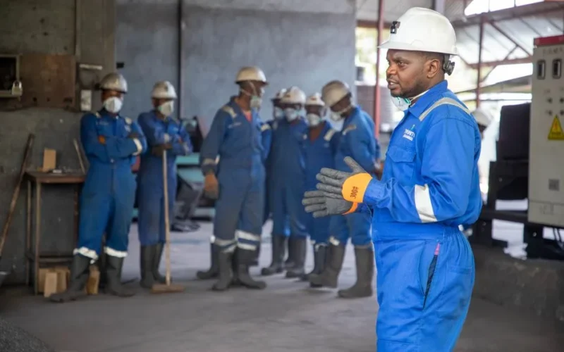 A group of factory workers in safety gear receiving training indoors.