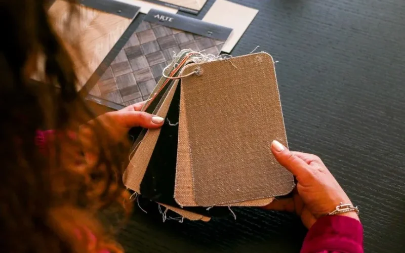Designer examining fabric swatches for interior design on a black table.