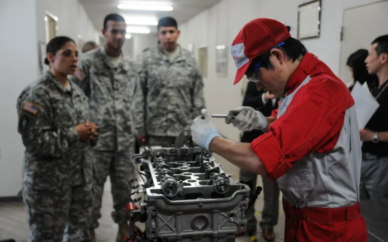 Soldiers from U.S. Army Japan watch Nissan automotive technician Shintaro Matsumoto reassemble a 1.6 Liter Peugeot engine with the speed and efficiency of a NASCAR pit crew during a VIP tour of Nissan's Zama Operations Center June 18, 2015, in Zama City, Japan. Nissan invited their distinguished guests in uniform to see firsthand its employees' craftsmanship while learning more about one another's culture, history and heritage. Matsumoto, a 20-year old who can diagnose, disassemble, repair and reassemble a car engine within 45 minutes, will represent Japan at the 2015 WorldSkills Olympics, the world's largest professional education event that attracts thousands of craftsmen from more than 50 countries to compete in various challenges from manufacturing and mobile robotics to hairdressing and graphic design. (U.S. Army photo by Sgt. John L. Carkeet IV, U.S. Army Japan) Unit: U.S. Army Japan DVIDS Tags: tour; Japan; trucks; engineering; respect; assembly line; engines; precision; automotive; mechanics; cars; Soldiers; vehicles; community; youth; Army; computers; Nissan; June; USARJ; U.S. Army Japan; CAD; 2015; Zama City; classic; I Corps (Fwd); WorldSkills Olympics; Zama Operations Center; World Heritage Collection; mechatronics; Datsun; Fairladies; Roadsters; Camp Zama City; Team Japan