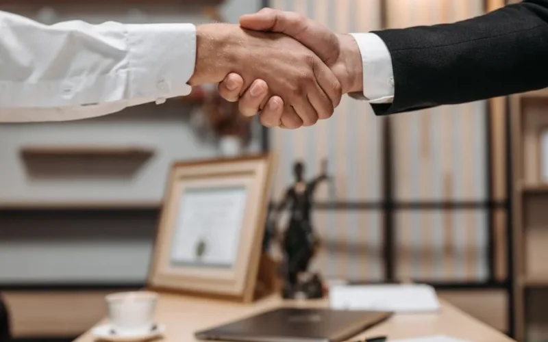 Close-up of a handshake between two professionals in a modern office setting, emphasizing partnership and agreement.