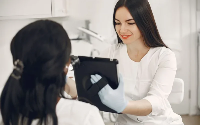 A beautician consults a client using a tablet in a modern beauty spa setting.