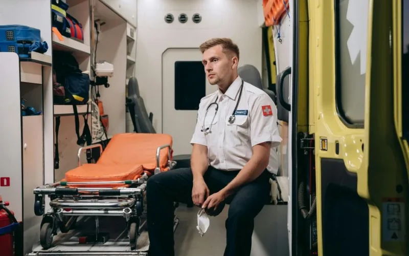 A paramedic sits in an ambulance van interior, exemplifying readiness for emergency medical services.