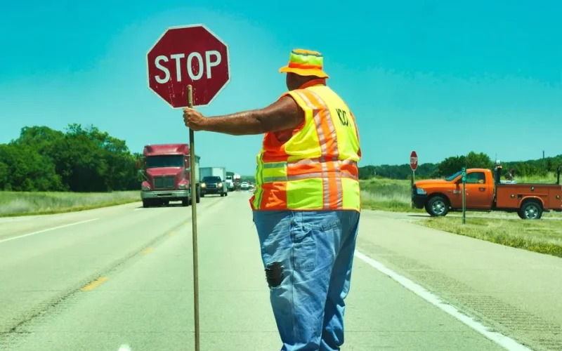 Road construction worker holding a stop sign on a highway ensuring traffic safety.