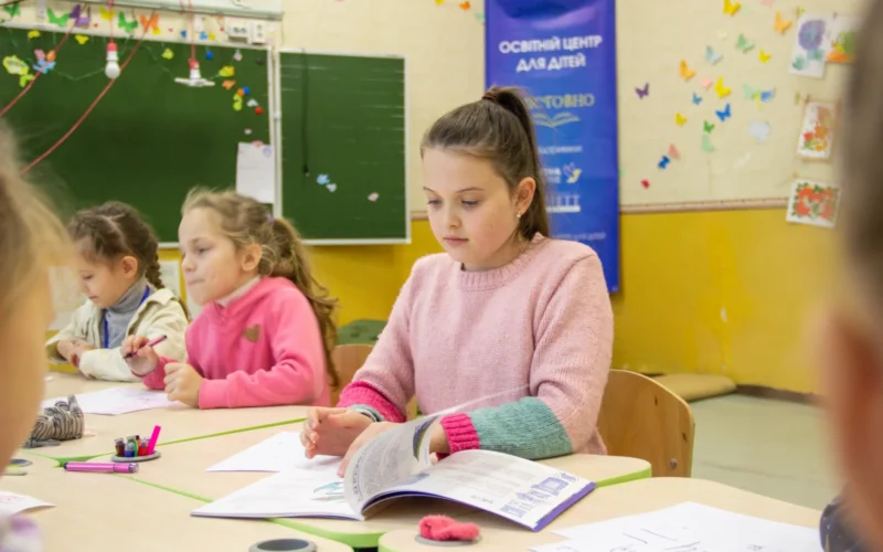 This photograph shows children in a Zmistovno after-school learning center, funded by The Howard G. Buffett Foundation with the support of Nova Ukraine. The program has established 55 centers across Eastern and Southern Ukraine to expand access to free, high-quality after-school education for children affected by the ongoing war. Each center is fully equipped with child-friendly furniture, educational materials, developmental toys, and technology (computers, monitors, TVs) to support both offline and online learning. Instructors and administrators conduct lessons, creative workshops, games, and group activities, ensuring continuity of education and providing psychosocial support in a safe environment.