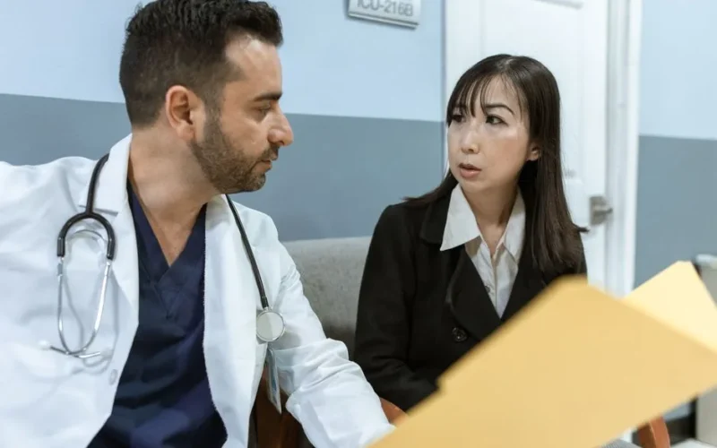 A doctor consults with a colleague in a hospital, examining medical documents.