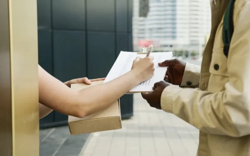 An outdoor scene of a package being delivered and a receipt being signed.