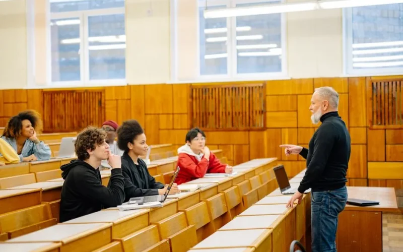 A diverse group of university students engaging with a professor during a classroom lecture.