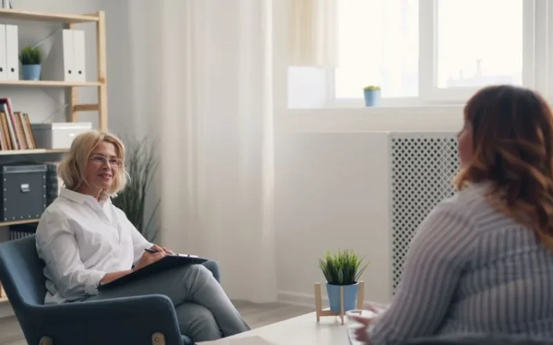 A therapist and a client engaging in a counseling session in a bright, modern office.