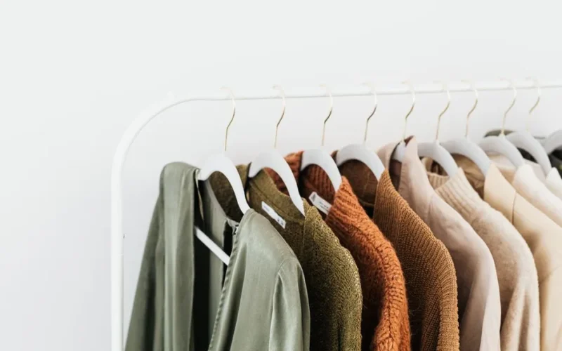 A minimalist display of colorful sweaters and shirts on white hangers.