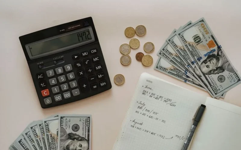 Flat lay of calculator, cash, coins, and handwritten notes for budget planning.