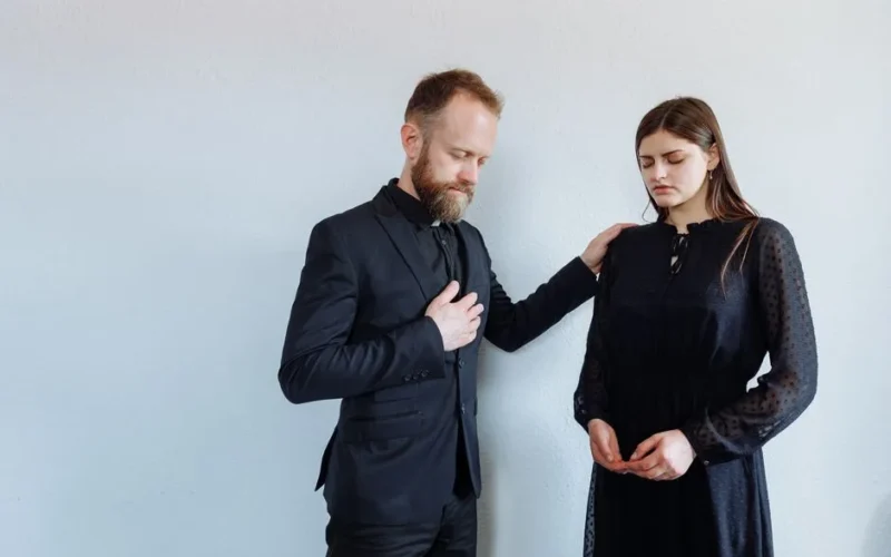 Priest offering support to grieving woman with a comforting gesture indoors.