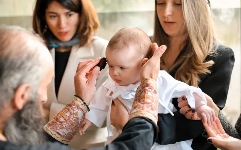 A touching moment during a baby's baptism, showcasing family and religious traditions.
