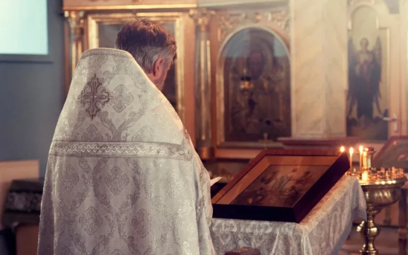 A priest distributes holy communion during a church ceremony indoors.