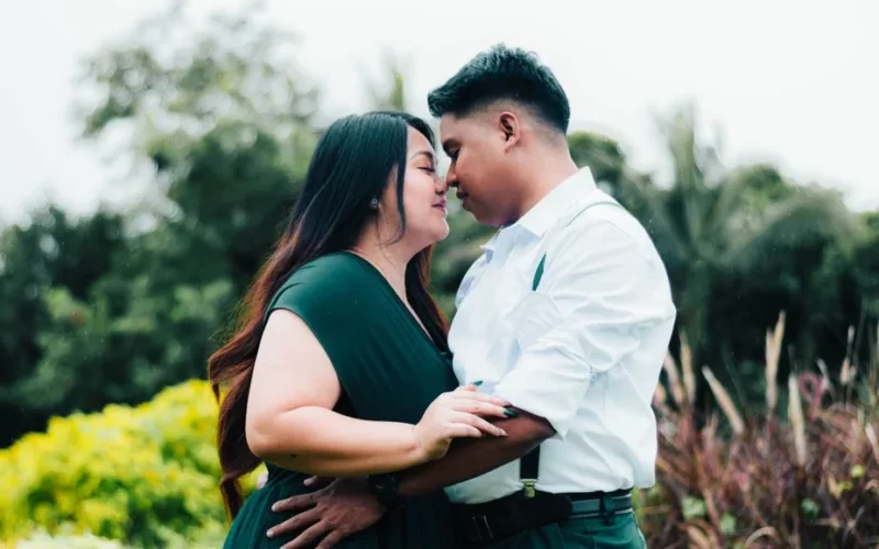 A romantic moment as a couple embraces lovingly in a lush outdoor setting.
