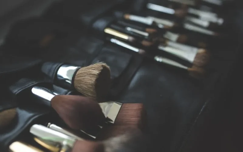 A stylish arrangement of makeup brushes set against a dark, elegant background.