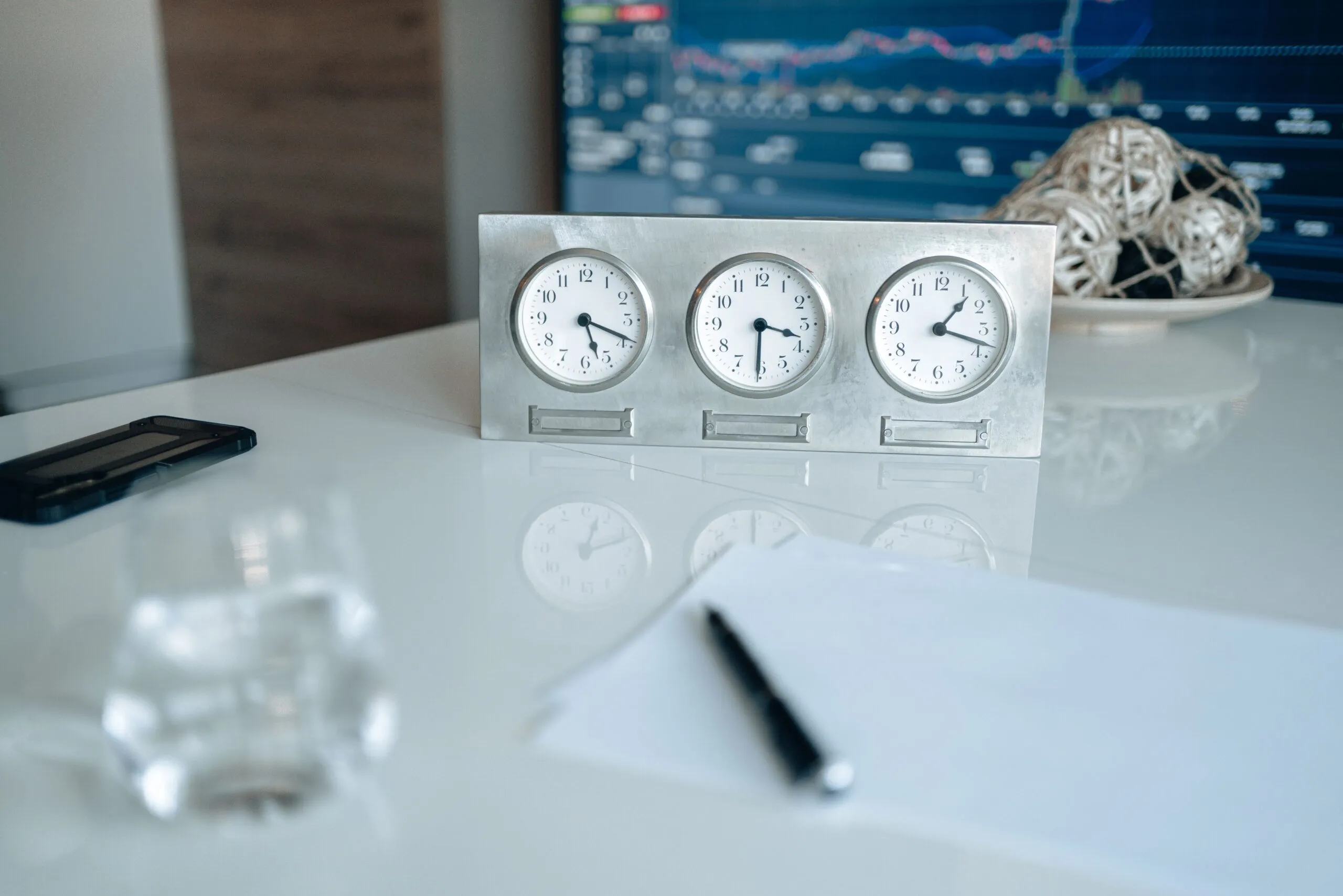 Professional workspace featuring three clocks and financial data on screen.